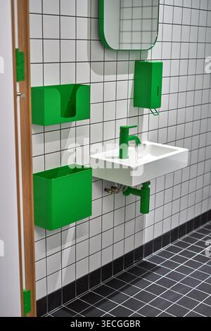 Modern restroom interior featuring a minimalist design with white square wall tiles and black floor tiles arranged in a grid pattern with contrasting Stock Photo