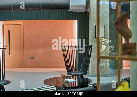 Modern interior design of a commercial or office space featuring a bold color palette with peach-orange walls and dark green corrugated paneling. The Stock Photo
