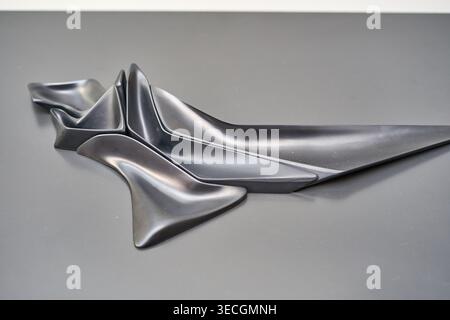 A close-up view of an abstract black sculptural object featuring smooth, flowing organic curves and multiple interconnected geometric forms. The Stock Photo