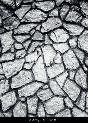 Black and white texture of a rustic stone wall with irregular rock patterns and cement joints Stock Photo