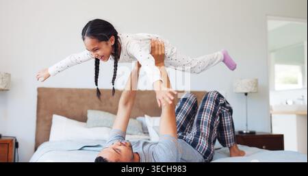 Laugh, flying and dad with child in bedroom for playing, bonding and relax together in morning. Family, home and father with girl for playful Stock Photo