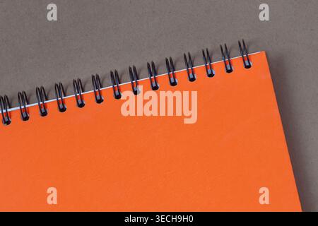 Orange spiral notebook on dark gray paper surface with empty cover for design. Concept of notebook planning, stationery, education, creative Stock Photo