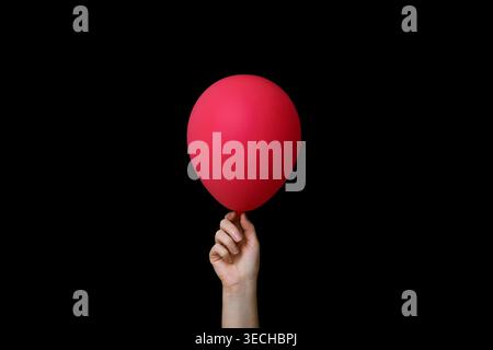 Hand Holding Red Balloon on Black Background Stock Photo