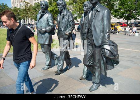Liverpool,United Kingdom-August 10 2022:Summertime along the city center Waterfront,the lifelike Beatle statues stand permanently,attracting visitors Stock Photo