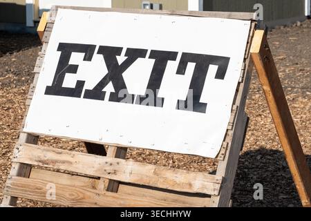 Horizontal photo of an ‘EXIT’ sign on a wooden surface, highlighting rustic signage with natural wood textures Stock Photo