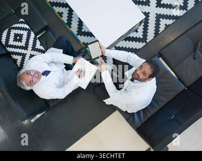 Middle Eastern doctors consulting in hospital lounge using tablet and notes during clinical discussion Stock Photo