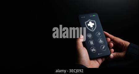 Hands holding smartphone with glowing health insurance app icons on dark copy space. Mobile healthcare, medical protection, digital hospital service, Stock Photo