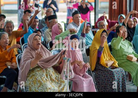A group of elderly residents enthusiastically participating in a communal activity at PPSLU Mandalika in Mataram, Indonesia. Stock Photo
