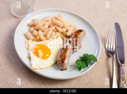 Portion of breakfast food is fried egg and pork sausage with stewed beans Stock Photo