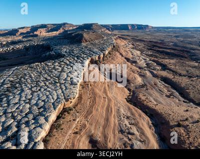 Aerial view of unique white rock formations and layered sandstone cliffs under a clear blue sky. Stock Photo