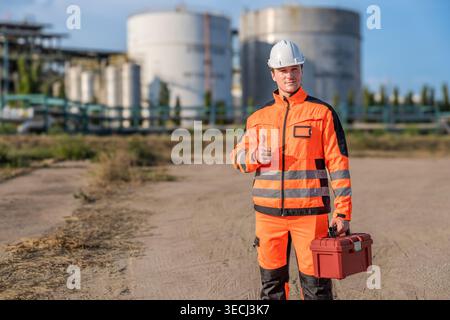 Successful Caucasian male engineer in high-vis uniform approves site safety at a plant for quality assurance and industrial service marketing. Stock Photo