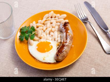 Portion of breakfast food is fried egg and pork sausage with stewed beans Stock Photo