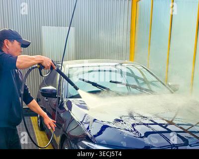 A man washes a car at a self-service car wash. Car wash concept Stock Photo