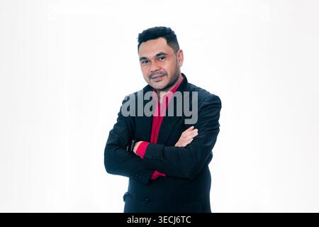 Portrait of a confident Indonesian professional man in a suit standing with arms crossed, isolated on white background. Stock Photo