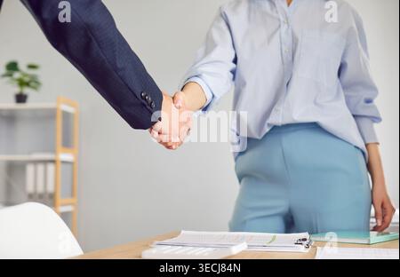 Business people standing in office on workplace making a deal. Man shaking hand with woman. Stock Photo