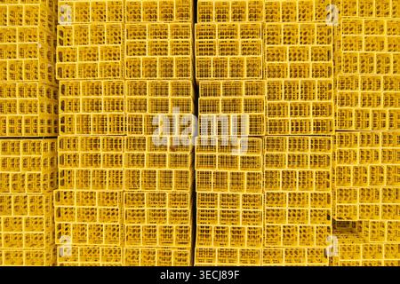 Aerial view of stacked yellow plastic crates arranged in a dense grid pattern in an industrial storage area. Stock Photo