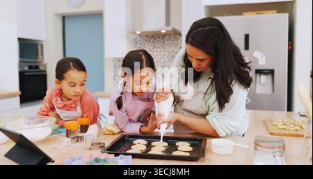 Mom, help and baking with children in kitchen, development and cookie decoration with icing in home. Teaching, kids and recipe for dessert preparation Stock Photo