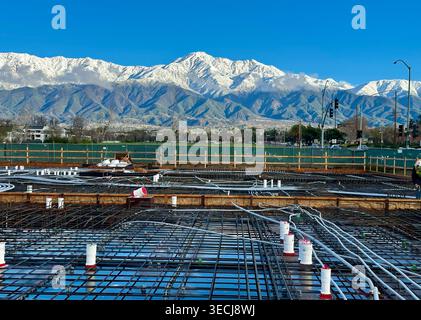 Construction podium slab with rebar and utilities under construction with snow mountains in background Stock Photo