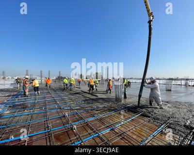 Construction workers pouring concrete slab at a commercial job site Stock Photo