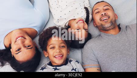 Portrait, above and parents with children on bed for love, bonding and relax together in morning. Family, home and happy mom, dad and kids for Stock Photo
