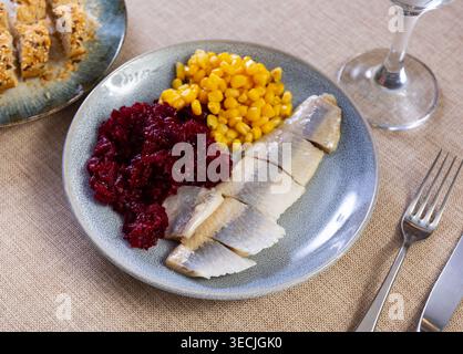 Herring served on plate with grated beetroot and corn Stock Photo