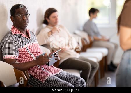 Middle-aged man sitting in a queue at a modern office Stock Photo