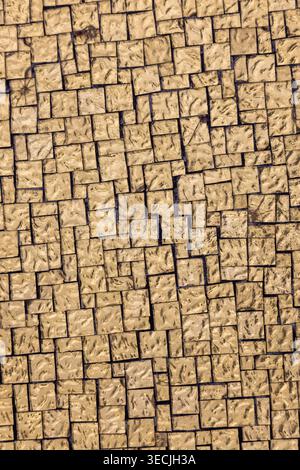 Top view of beige stone pavement with small square tiles forming a geometric pattern. Natural textured surface ideal for backgrounds, design, architec Stock Photo