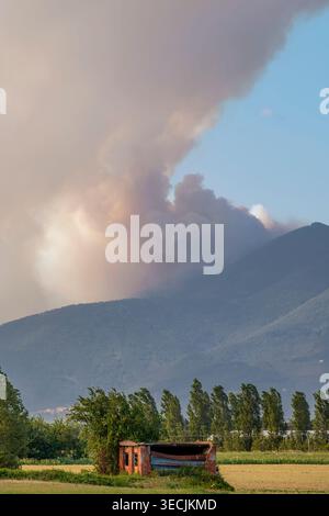 A ruin in the Tuscan countryside in the province of Pisa, Italy, with Mount Faeta in the background during a large forest fire Stock Photo