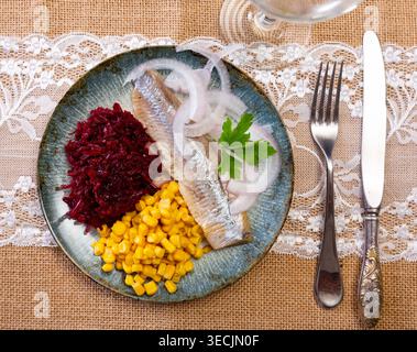 Herring served on plate with grated beetroot and corn Stock Photo