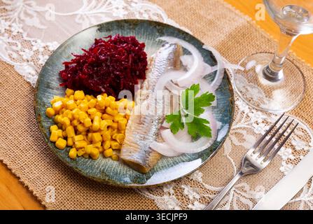 Herring served on plate with grated beetroot and corn Stock Photo