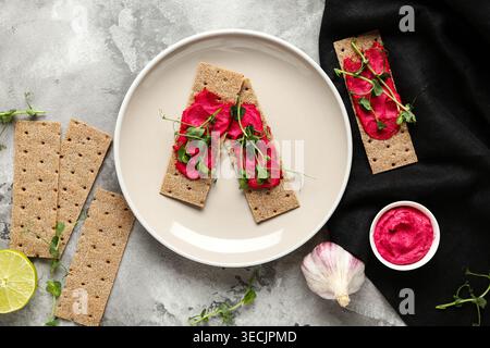 Plate with crispbreads, tasty beetroot hummus and microgreen on grunge background Stock Photo