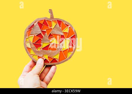 kid hands hold crafts mosaic against a gray background. mosaic master. childrens creative Stock Photo