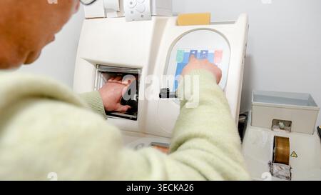 A professional at an optical center uses precision equipment to craft lenses for glasses. The machine ensures high customer satisfaction by delivering Stock Photo