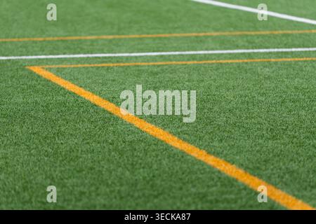 Detailed close-up of green artificial turf showing white and yellow painted lines, a clean sports field surface background with copy space for design Stock Photo