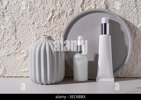 Elegant display of cosmetic bottles on a smooth surface against a textured concrete wall. The composition showcases a minimalist aesthetic, emphasizin Stock Photo