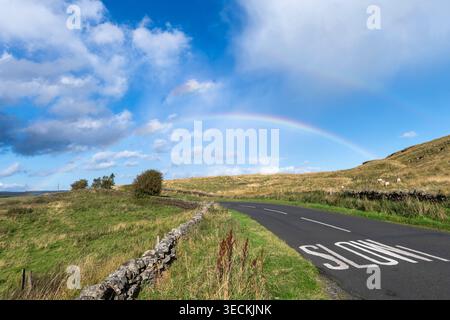 Rainbow over the road in northern England. Stock Photo