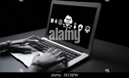 A robotic hand interacts with a laptop displaying icons for software as a service, reflecting innovation, digital technology, and the future of work Stock Photo