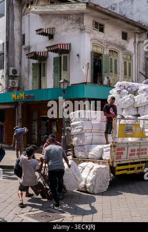 Labourers move goods from truck to shop in the textiles area in central Medan. Stock Photo