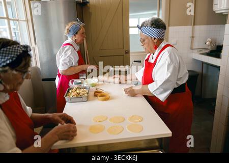 Senior Caucasian and Black women chefs preparing dough in a commercial kitchen setting Stock Photo