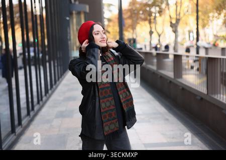 Joyful young woman enjoying a sunny autumn day in an urban setting with a stylish beret and cozy scarf Stock Photo