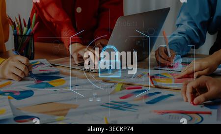 A diverse team engages in collaborative work at a table, focusing on data security and innovative strategies while utilizing laptops and colorful Stock Photo