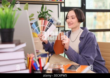 Creative designer joyfully exploring color palettes while working in a bright studio setting on a sunny day Stock Photo