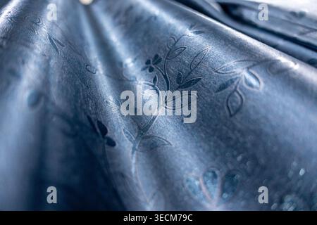 Close up abstract macro view showing corrugated dark blue metal sheet with stamped floral leaf pattern creating calm textured background surface captu Stock Photo