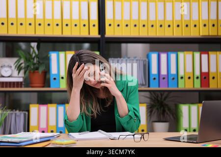 Stressed professional struggling with workload in a colorful office setting during a busy workday Stock Photo