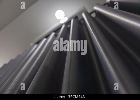 Dark grey curtain drape hanging from ceiling with deep vertical fold and soft light creating calm mysterious shadow across heavy textile material insi Stock Photo