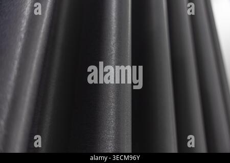 Close up of dark fabric curtain showing smooth texture and deep fold. black elegant wave and drape create moody and calm backdrop for modern interior Stock Photo