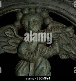 Square close detail of curly-haired, clear-eyed angelic piper with widespread wings playing divine music symbolising praise, joy and harmony in left leaf of gates in green altar rails of 15th century CE Chapel of St Anne at Daoulas, North Finistère, Brittany, France.  Chapel served hospice hosting Christian pilgrims travelling to Christian shrines at Rocamadour and Santiago de Compostela. Stock Photo