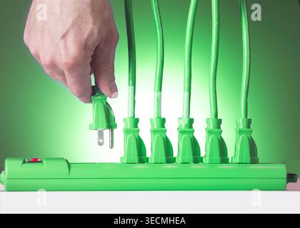 Hand plugging in multiple electrical cords in to power strip, USA Stock Photo