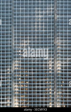 Full frame overhead shot of a galvanized steel floor grating system featuring a vertical geometric pattern and repeating square grid for industrial dr Stock Photo
