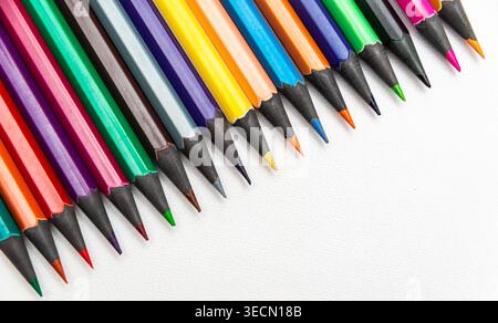 A collection of pencils is lined up on a plain surface with bright tips showing during the day, creating a vibrant scene. Stock Photo